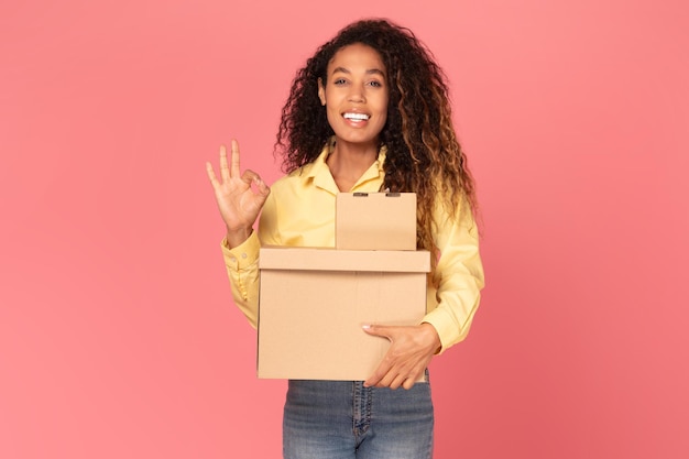 Foto jovem mulher negra segurando uma encomenda fazendo gestos de 