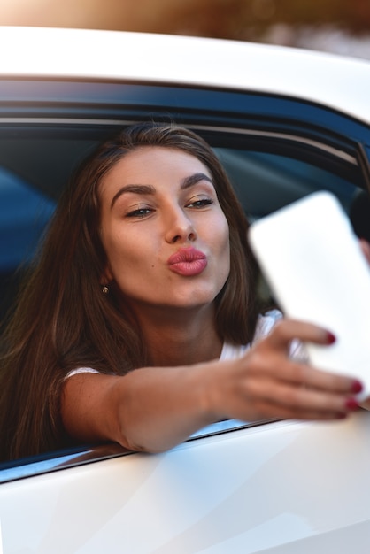 Jovem mulher no carro vai de férias como passageira faz selfie.