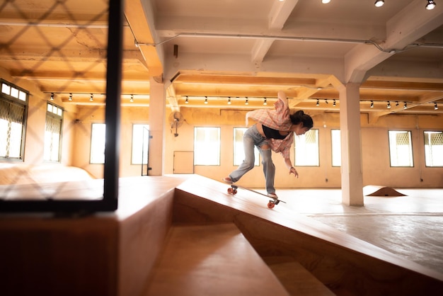 Jovem mulher no estilo de vida de skate esportivo adolescente feliz se divertindo com skate no esporte ginásio hipster moda atividade urbana na moda