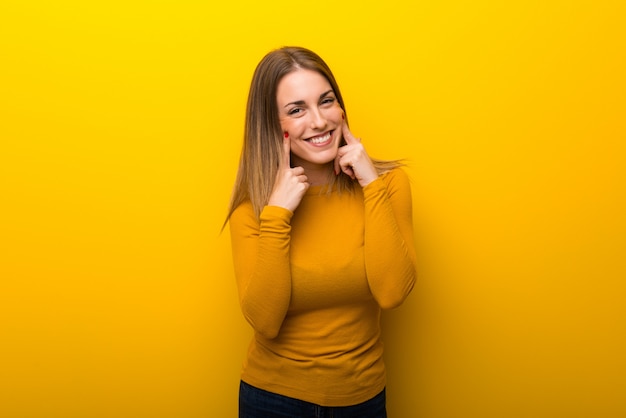 Jovem mulher no fundo amarelo que sorri com uma expressão feliz e agradável