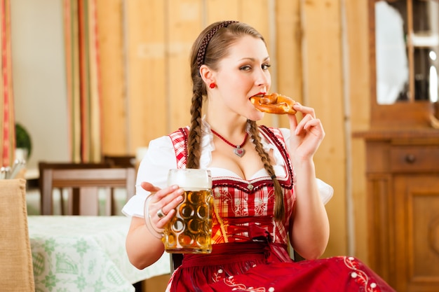 Jovem mulher no Tracht tradicional da Baviera no restaurante ou pub
