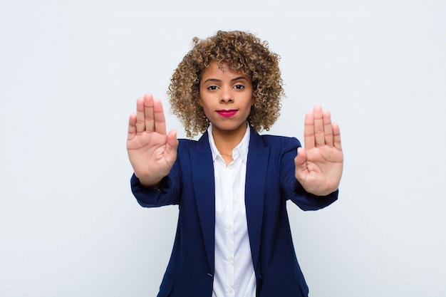 Foto jovem mulher olhando a entrada de proibição séria, infeliz, irritada e descontente ou dizendo pare com as duas palmas abertas contra a parede plana