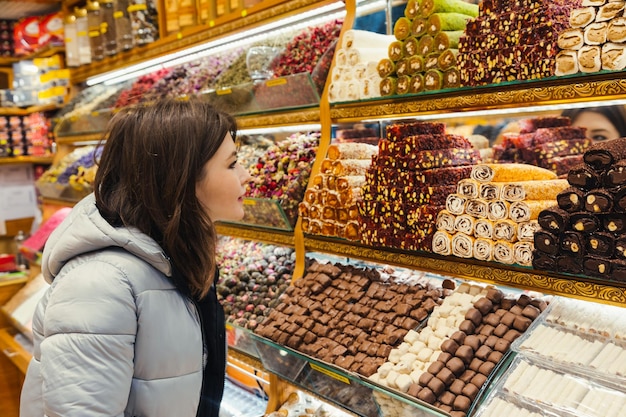 Jovem mulher olhando para a delícia turca vários doces coloridos lokum e chocolate na loja que vende delícia