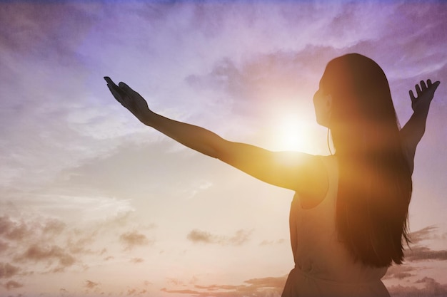 Foto jovem mulher olhando para cima sentindo-se energizada pelos raios quentes e pelo céu