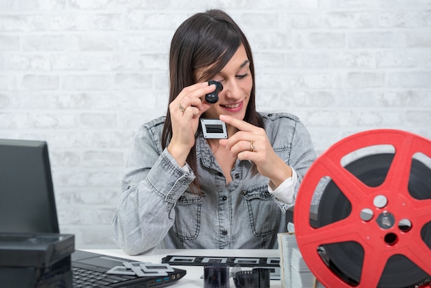 Jovem mulher olhando slide de filme com lupa