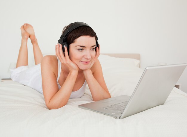 Jovem, mulher, ouvindo música com seu laptop