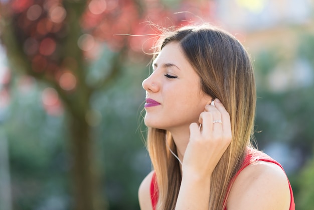 Jovem mulher ouvindo música em um parque