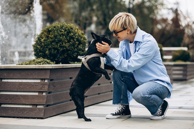 Jovem mulher passeando com seu buldogue francês de estimação