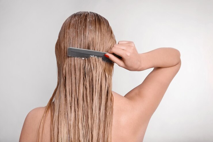 Foto jovem mulher penteando o cabelo coberto com máscara em fundo claro