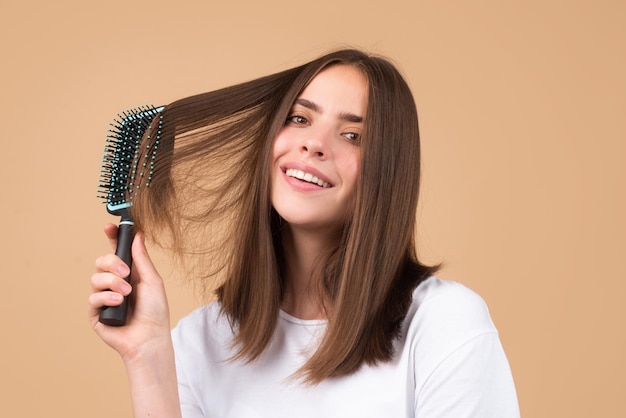 Jovem mulher penteando um cabelo saudável e natural e brilhante, isolado em um estúdio de beleza, cuidados com os cabelos