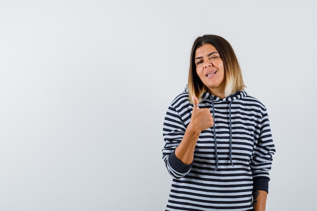 Jovem mulher piscando os olhos e mostrando um bom sinal de mão no fundo branco