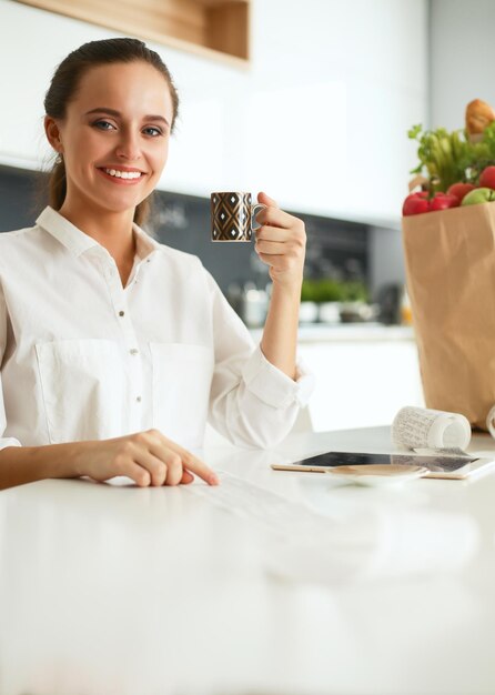 Jovem mulher planejando despesas e pagando contas em sua cozinha