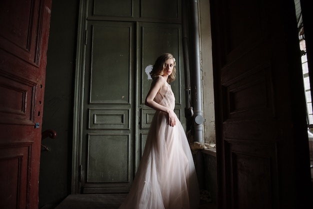 Jovem mulher posando em um vestido longo leve rosa concurso dentro de casa