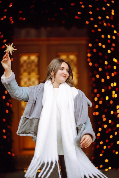 Jovem mulher posando junto à árvore de Natal nas férias de inverno com estrela de Natal.