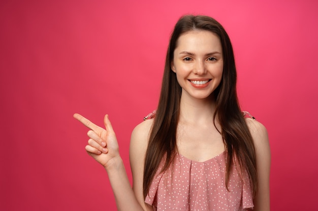 Jovem mulher positiva apontando o dedo para o espaço da cópia