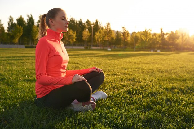 Foto jovem mulher pratica ioga ao nascer do sol no parque