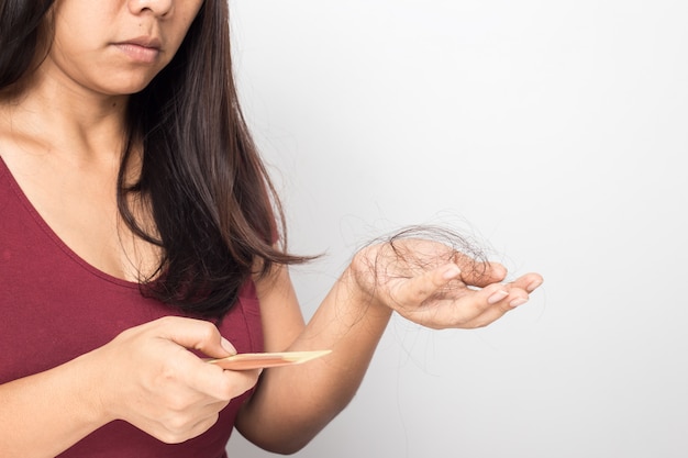 Jovem mulher preocupada com a perda de cabelo em um fundo branco