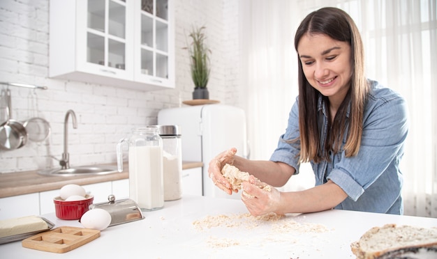 Jovem mulher prepara massa para bolos caseiros em uma espaçosa cozinha iluminada close-up.