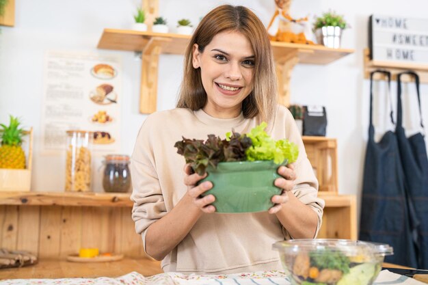 Jovem mulher preparando comida saudável com salada de legumes mulher sentada na despensa em uma bela cozinha interior A comida de dieta limpa de produtos e ingredientes locais Mercado fresco