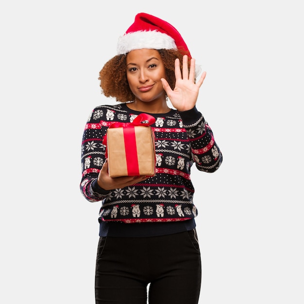 Jovem, mulher preta, segurando, um, presente, em, dia natal, mostrando, numere cinco