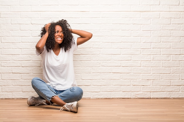 Jovem, mulher preta, sentando, ligado, chão madeira, louco, e, desesperado, gritando, descontrolado, engraçado, lunatic, expressar, liberdade, e, selvagem