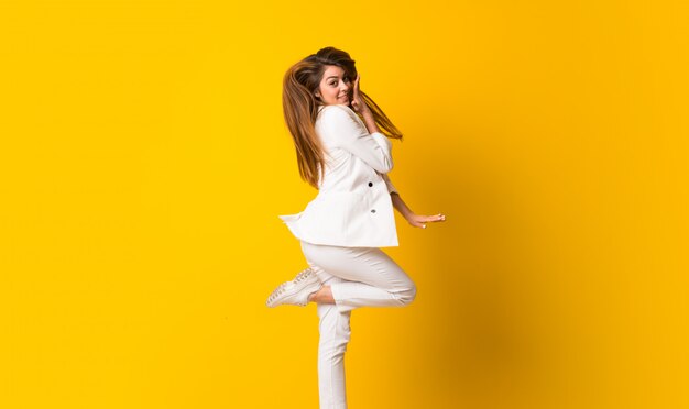 Jovem mulher pulando isolado na parede amarela