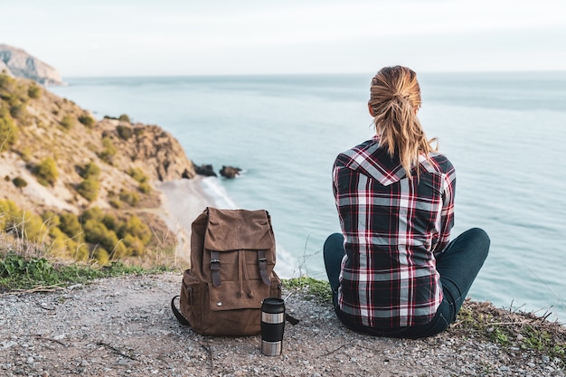 Jovem mulher quadril com uma mochila explora a costa em um lindo dia. Conceito de exploração e aventuras