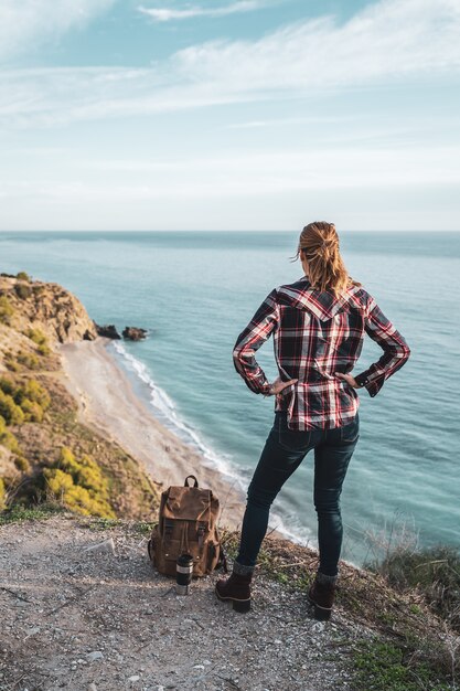 Jovem mulher quadril com uma mochila explora a costa em um lindo dia. Conceito de exploração e aventuras