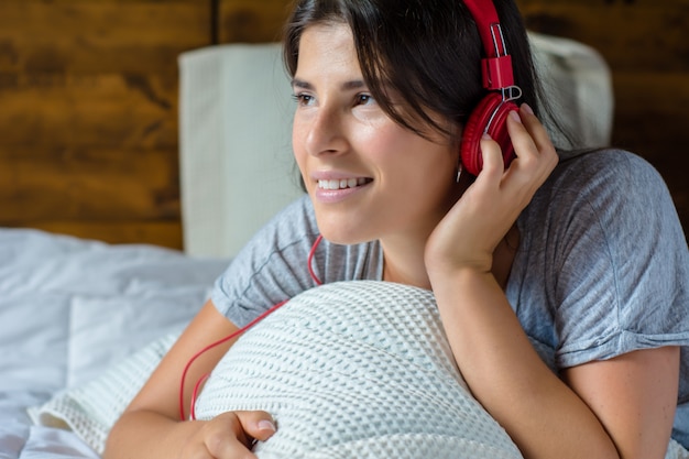 Foto jovem mulher que aprecia a música na cama.