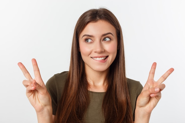 Jovem mulher que mostra dois dedos, positivo ou gesto da paz, no branco.