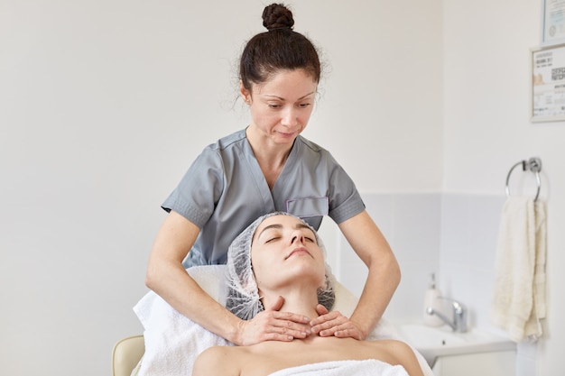 Jovem mulher que recebe o tratamento da massagem dos termas na clínica cosmetologic.