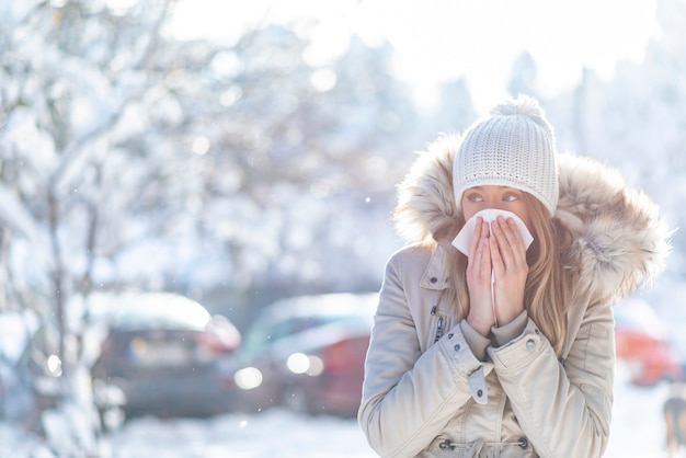 Foto jovem mulher que tosse durante o inverno na rua.