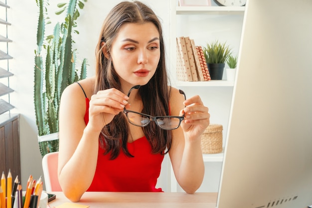 Jovem mulher que trabalha no escritório, usando o computador