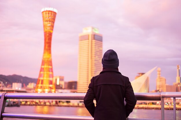 Jovem mulher que viaja no porto de kobe perto de osaka, viajante asiático feliz que olha edifícios modernos bonitos no por do sol. marco e popular para atrações turísticas em kobe, hyogo, japão.