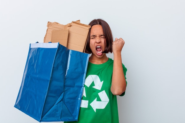 Jovem mulher reciclando papelão isolado na parede branca levantando o punho após uma vitória, conceito vencedor