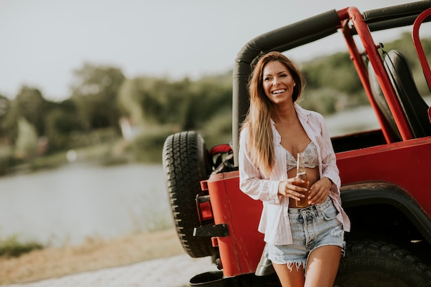 Jovem mulher relaxante de carro na beira do lago