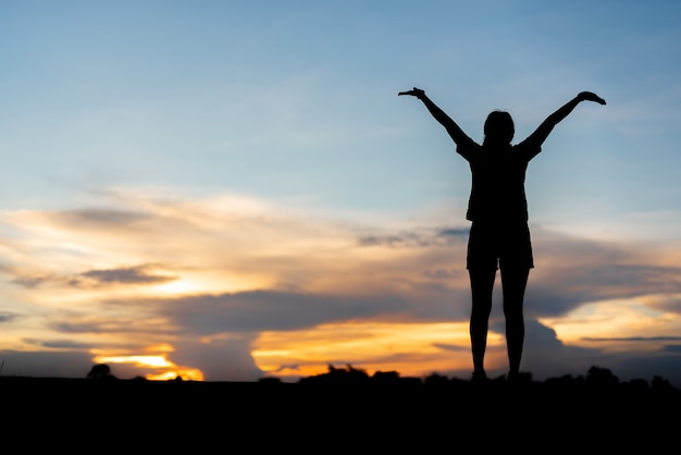 Jovem mulher relaxante whit pôr do sol céu ao ar livre.