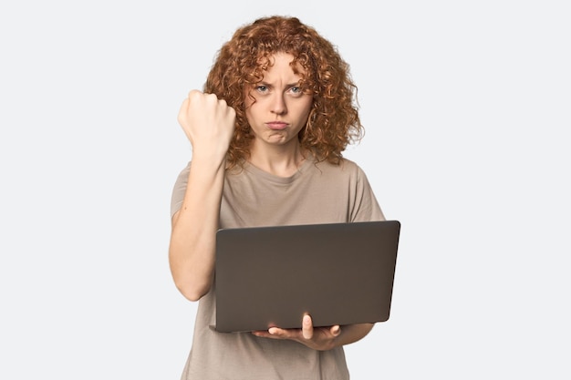 Foto jovem mulher roxa caucasiana com laptop mostrando punho para a câmera expressão facial agressiva