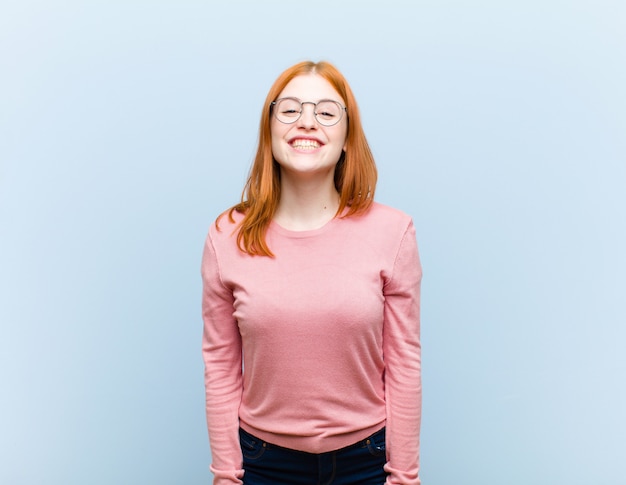 Jovem mulher ruiva bonita olhando feliz e pateta com um sorriso largo, divertido e maluco e olhos bem abertos