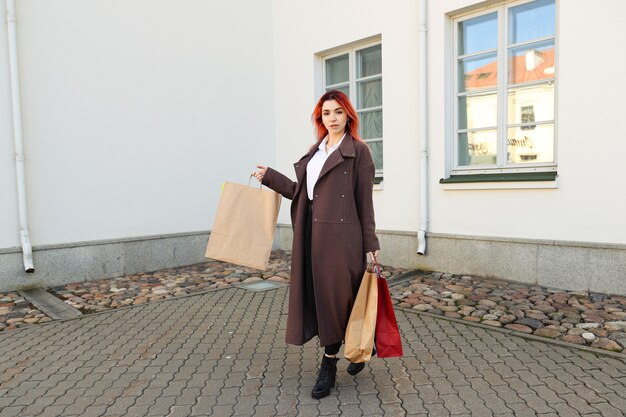 Jovem mulher ruiva com sacolas depois de fazer compras no shopping