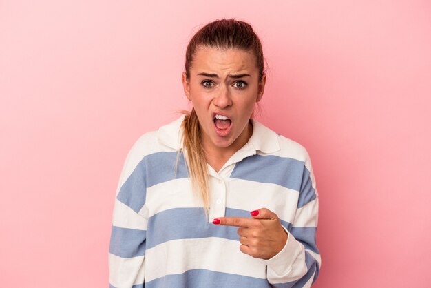 Jovem mulher russa isolada em um fundo rosa animado segurando um espaço de cópia na palma da mão.