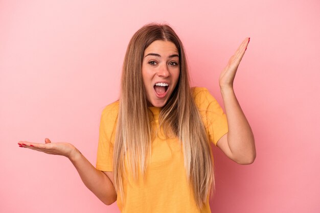 Jovem mulher russa isolada em um fundo rosa feliz, sorridente e alegre.