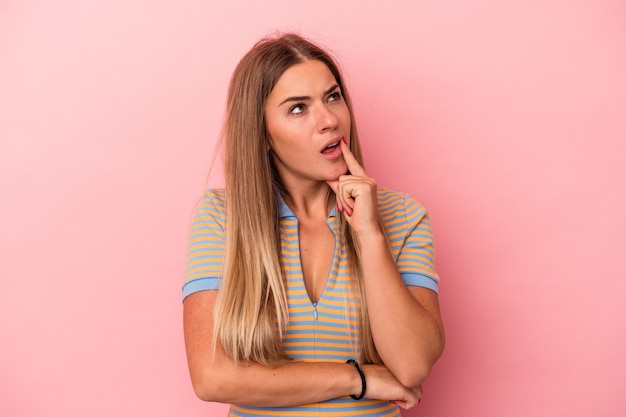 Jovem mulher russa isolada em um fundo rosa, segurando um espaço de cópia na palma da mão.