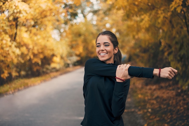 Jovem mulher saudável que aquece-se fora.