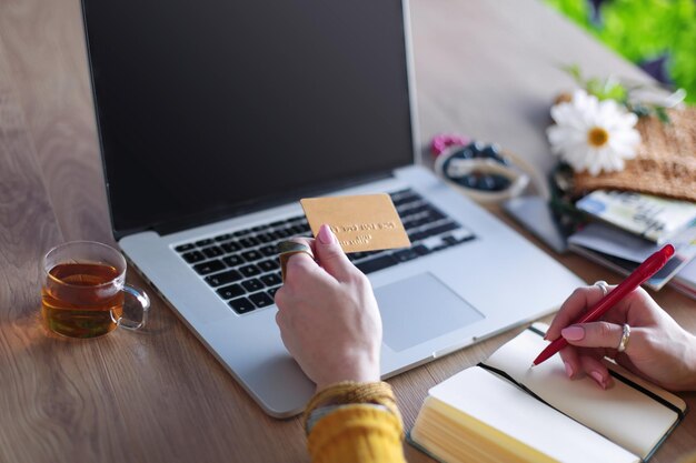 Jovem mulher segurando cartão de crédito e usando computador portátil Conceito de compras online