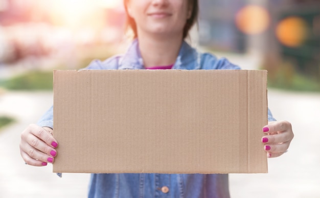 Jovem mulher segurando cartaz em branco nas mãos dela fechar