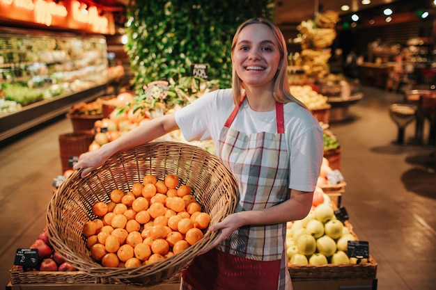 Jovem mulher segurando cesta de frutas na mercearia