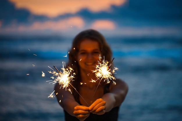 Jovem mulher segurando diamante celebrando a véspera de ano novo na praia