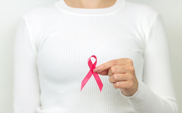 Jovem mulher segurando fita rosa de conscientização do câncer de mama. conceito do dia mundial do câncer