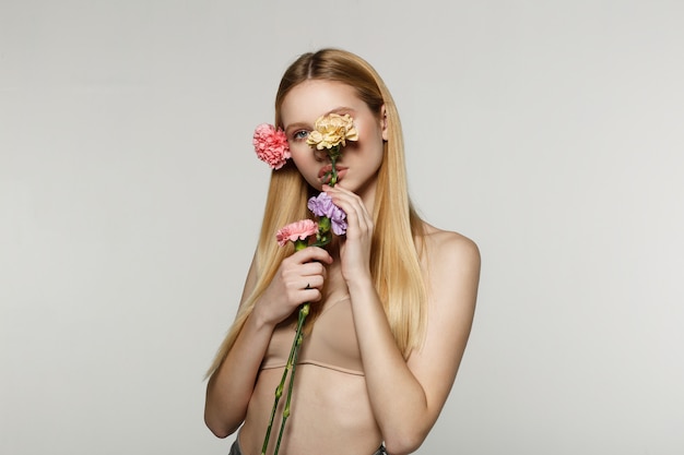 Jovem mulher segurando flores e posando em um estúdio